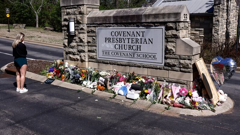 FILE - A woman pauses as she visits a memorial at the entrance to The Covenant School, March...